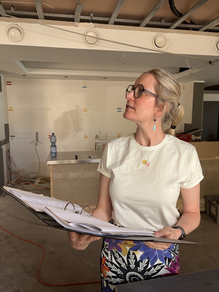 Bernadette Eggersglüß mit einem Ordner in der Hand auf der Baustelle des Restaurants Marktwächterin in Achim. 